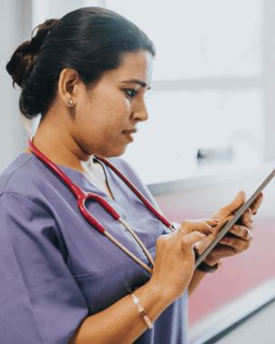 Female nurse in scrubs using a tablet in a hospital setting – SIFE pathway UK nursing