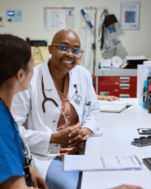 Smiling doctor in a white coat talking with a colleague in a medical office